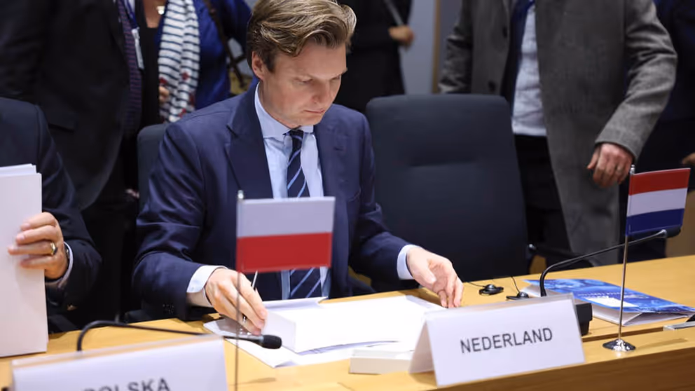 Minister Brekelmans tijdens vergadering achter naambordje van Nederland.