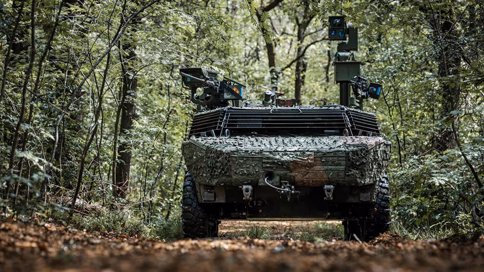 Gecamoufleerd militair voertuig rijdt door een bos