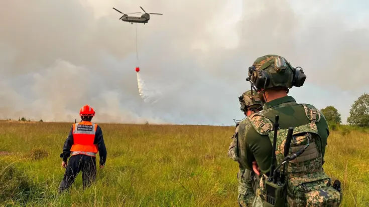 Brandweer en militairen kijken naar een blussende Chinook.
