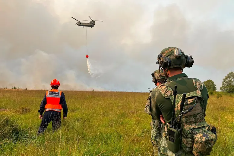 Brandweer en militairen kijken naar een blussende Chinook.