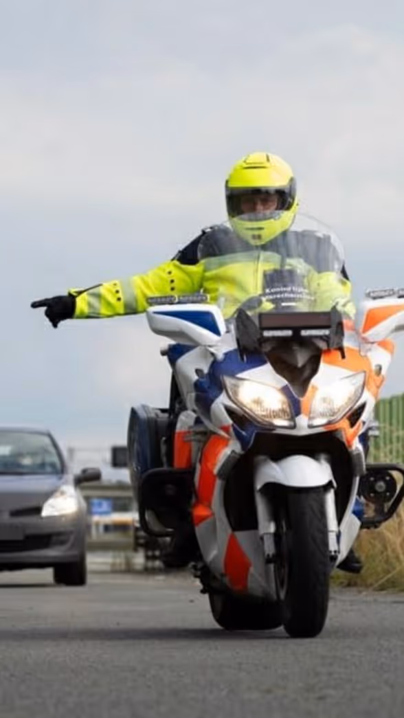 Motorrijder wijst een auto naar de zijkant van de weg