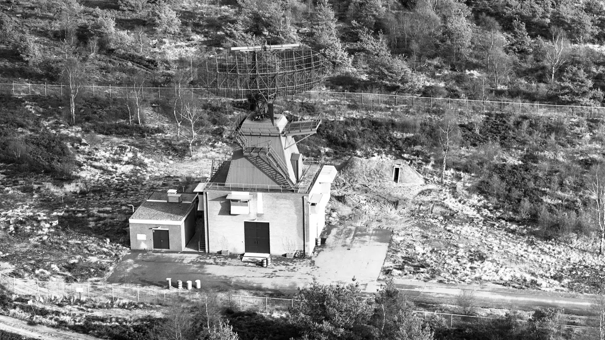 Zwart-witfoto vanuit de lucht van een radarinstallatie in een bos- en heidelandschap.