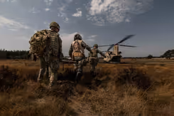 Militairen lopen met brancard naar Chinook-transporthelikopter.