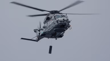 Links een NH90 maritieme helikopter met daaronder een sonar. 