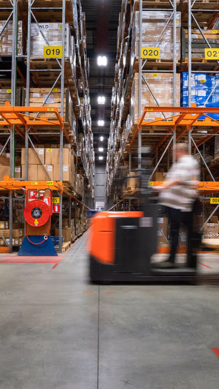 Een man rijdt op een voertuig door een opslagdepot.