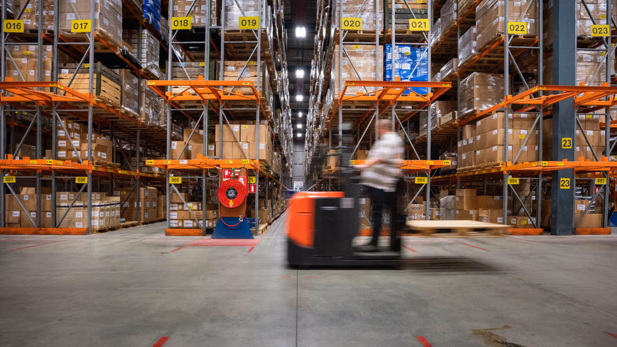 Een man rijdt op een voertuig door een opslagdepot.
