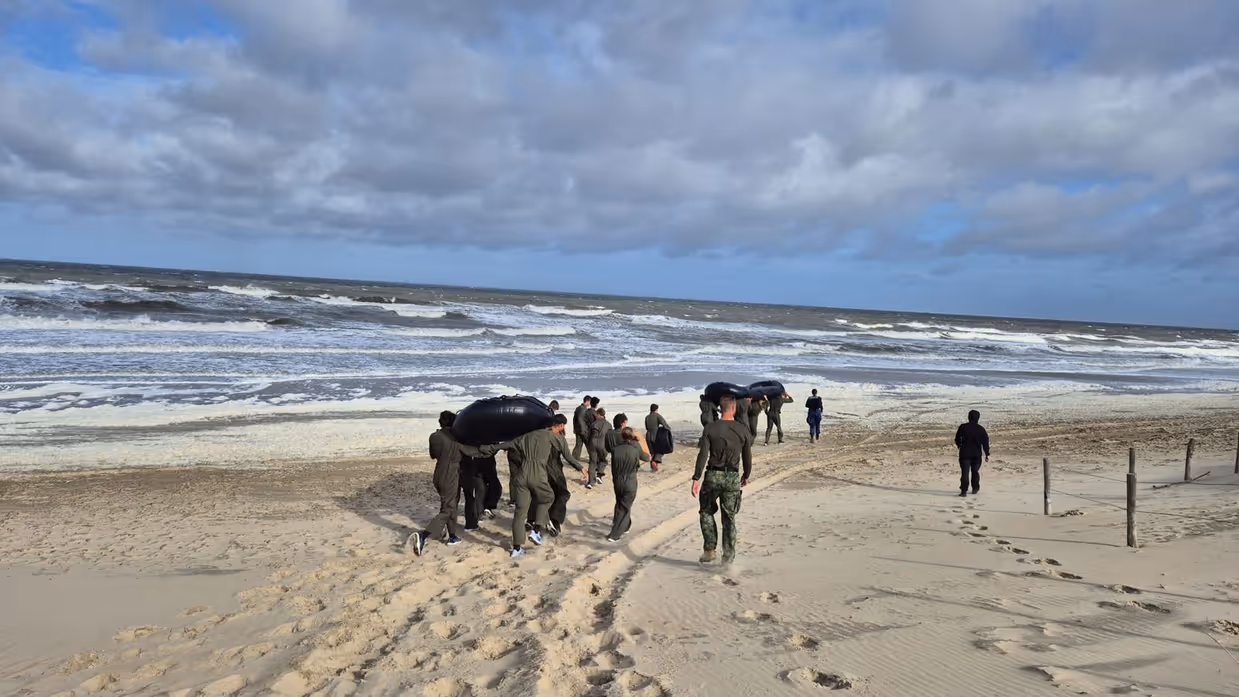 VEVA-leerlingen lopen langs de vloedlijn op het strand.