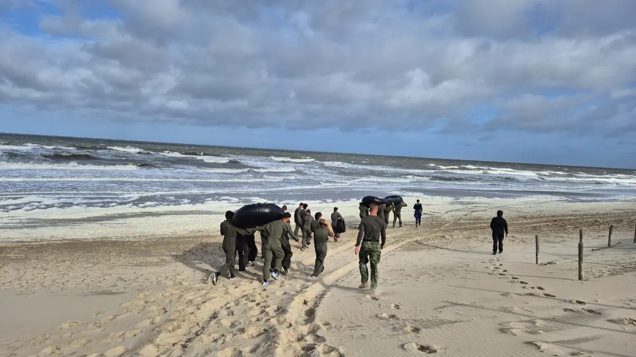 VEVA-leerlingen lopen langs de vloedlijn op het strand.