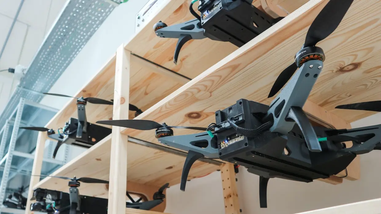 Een houten stellage waarin verschillende drones zijn geplaatst.