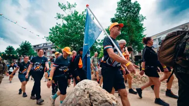 Een groepje wandelaars met dezelfde kleding. Een van hen draagt een blauwe vlag.