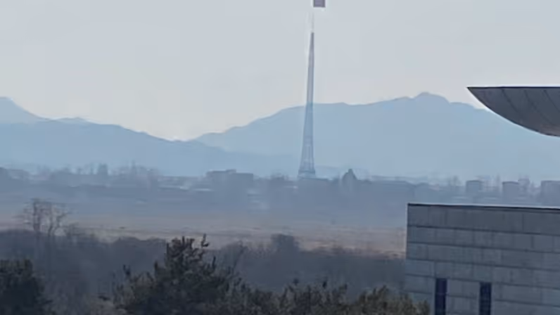 Een gebergte met daarop in de verte een wapperende vlag.  