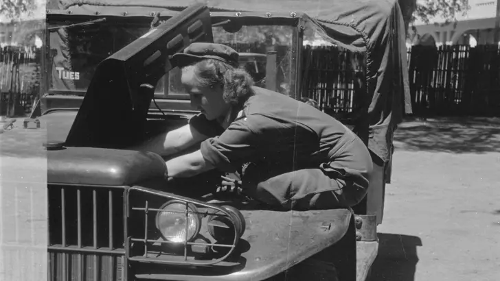 De vrouwelijke chauffeur Willinck kijkt in de motor van een voertuig.