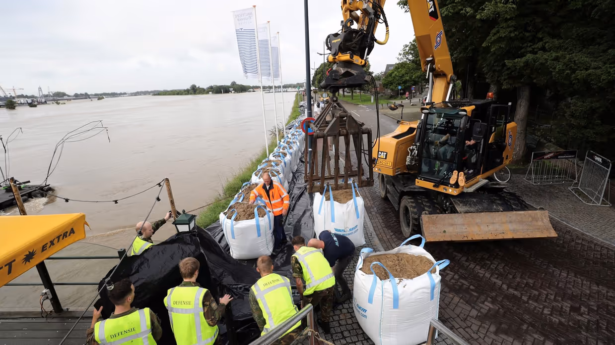 Militairen helpen bij het plaatsen van zandzakken.