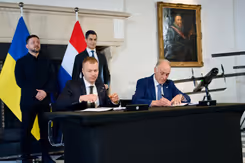 Het contract wordt ondertekend. Daarachter staan Zelensky en Jetten. 