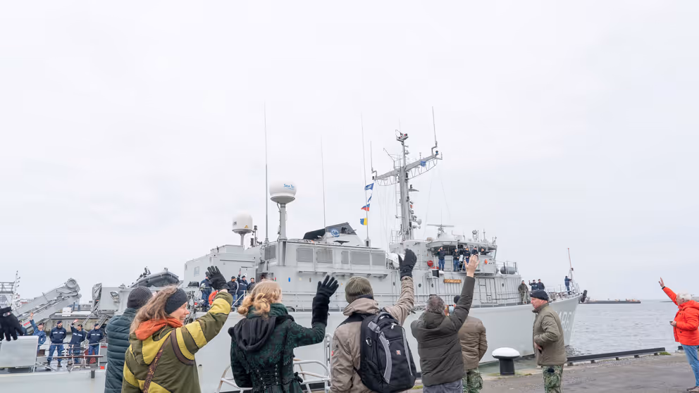 Op de kade zwaaien de thuisblijvers naar de bemanning op het schip.