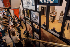 Overzicht van de opening van de tentoonstellingen met een spreker en een aantal foto's in beeld. 