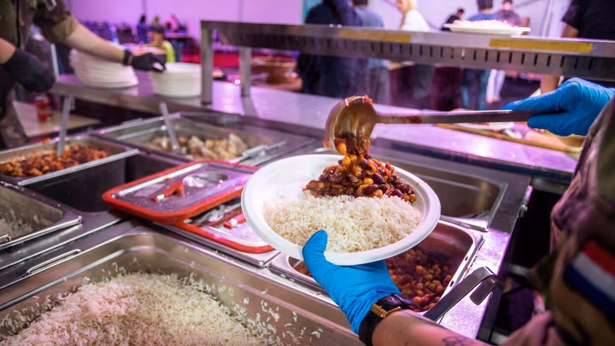 Militair schept bord rijst met chili op.