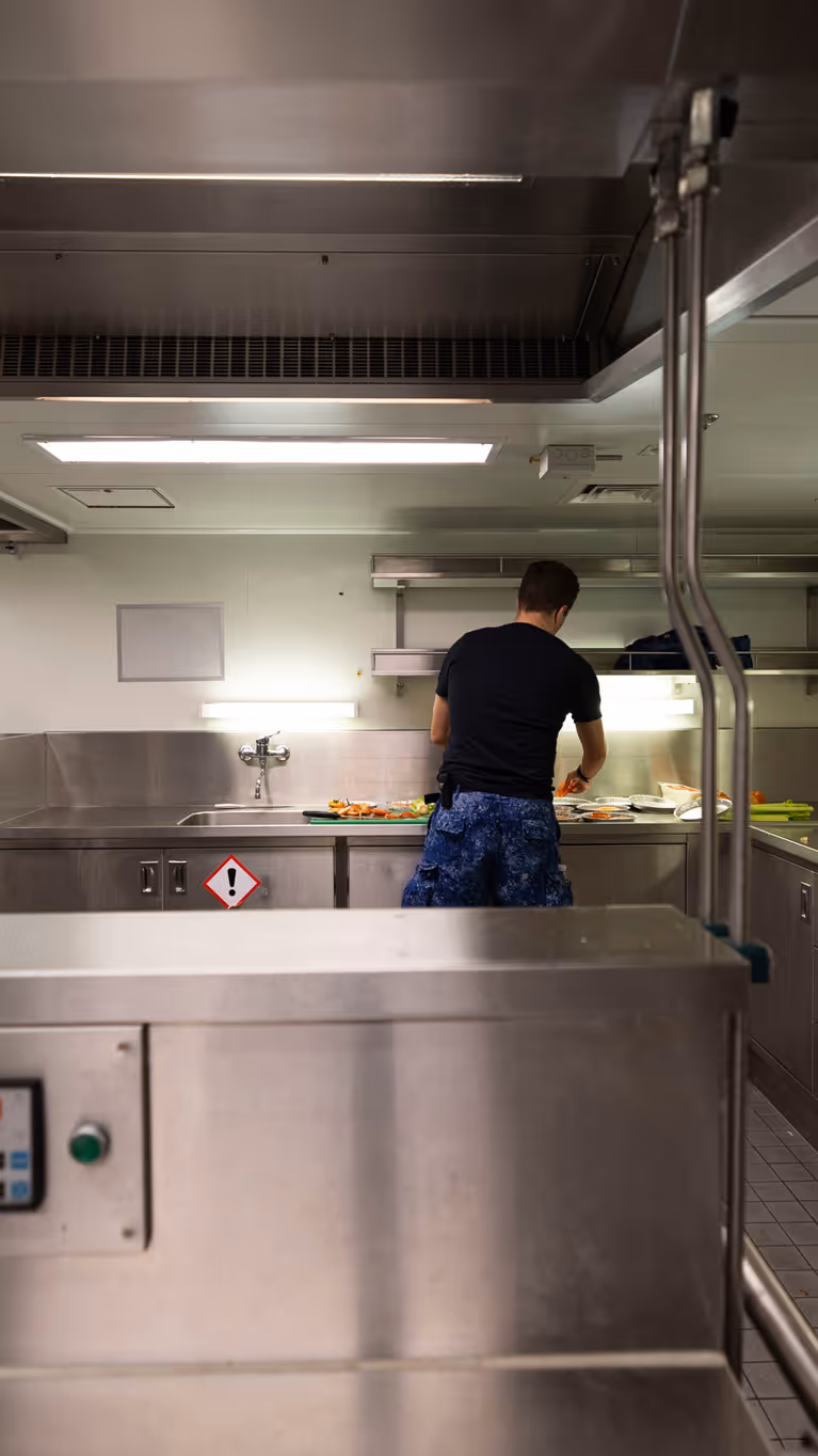 Een kok is aan het werk in een chromen keukenomgeving.