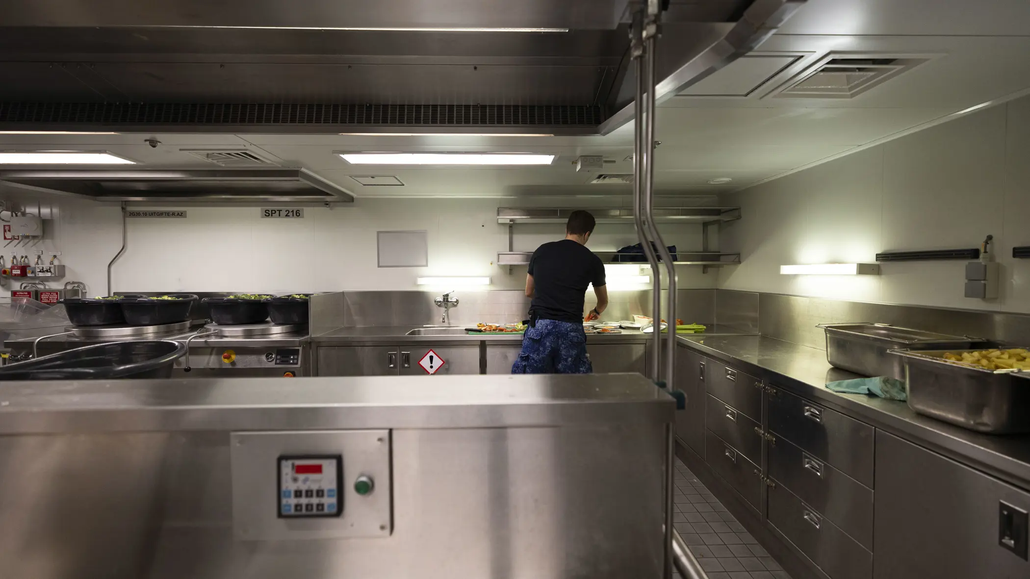 Een kok is aan het werk in een chromen keukenomgeving.