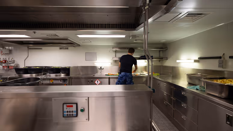 Een kok is aan het werk in een chromen keukenomgeving.