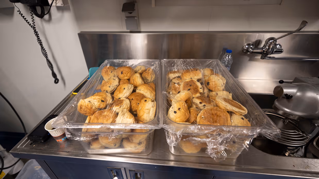 Een plastic bak met krentenbollen.