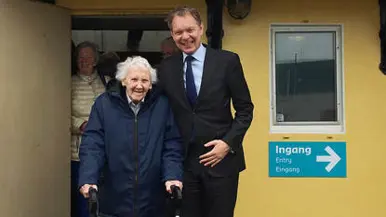 een oude dame met looprek voor een schip