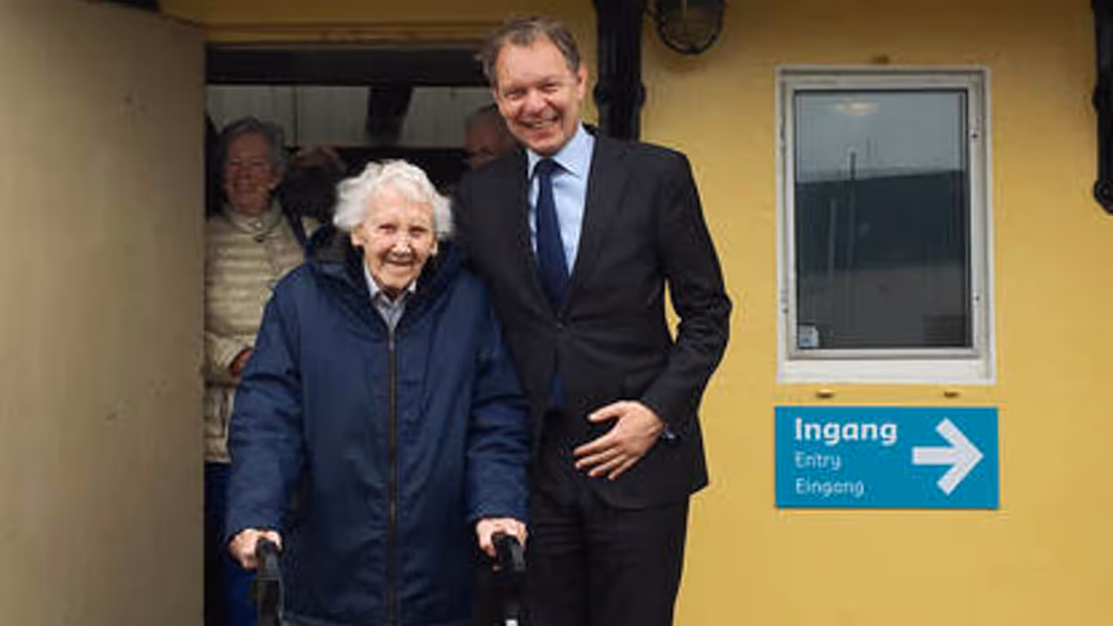een oude dame met looprek voor een schip