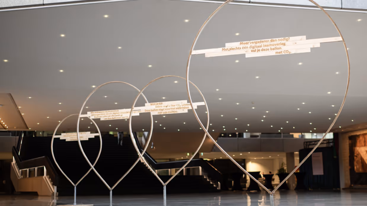 4 doorzichtige stalen ballonnen figureren in een grote hal. 