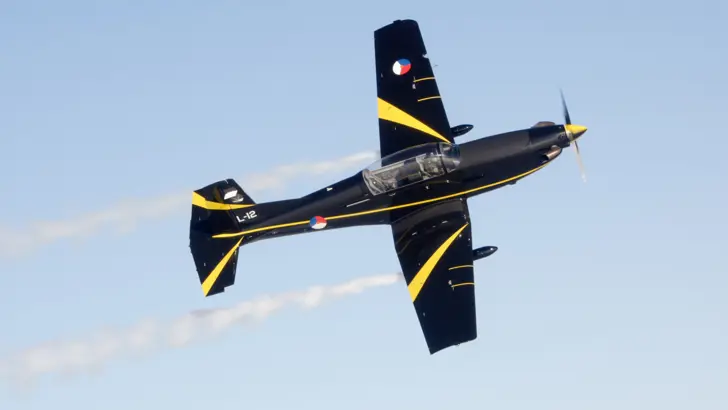 Bovenaanzicht van PC-7 lesvliegtuig in de lucht.