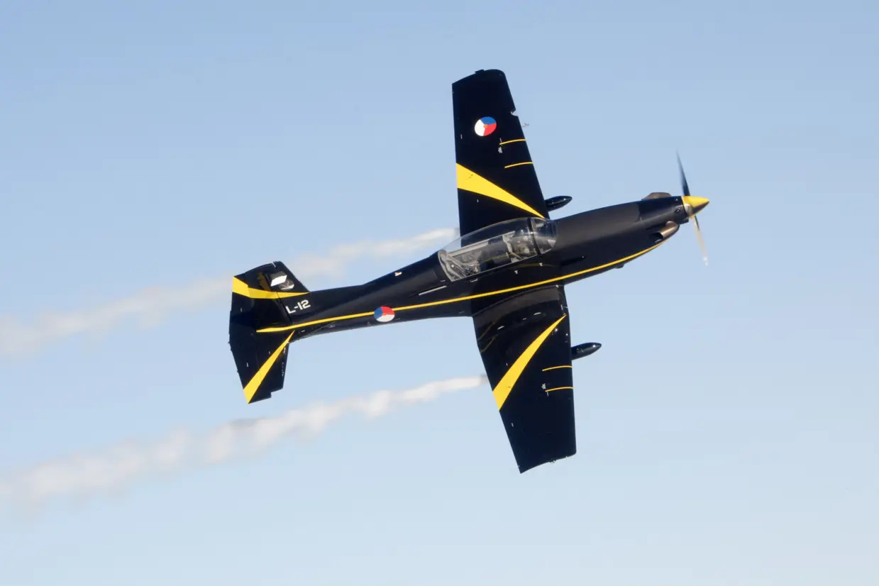 Bovenaanzicht van PC-7 lesvliegtuig in de lucht.