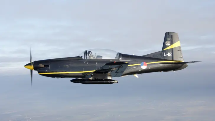 Zijaanzicht van PC-7 lesvliegtuig in de lucht.