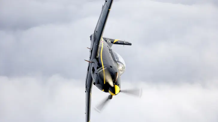 Zijaanzicht PC-7 in de lucht.