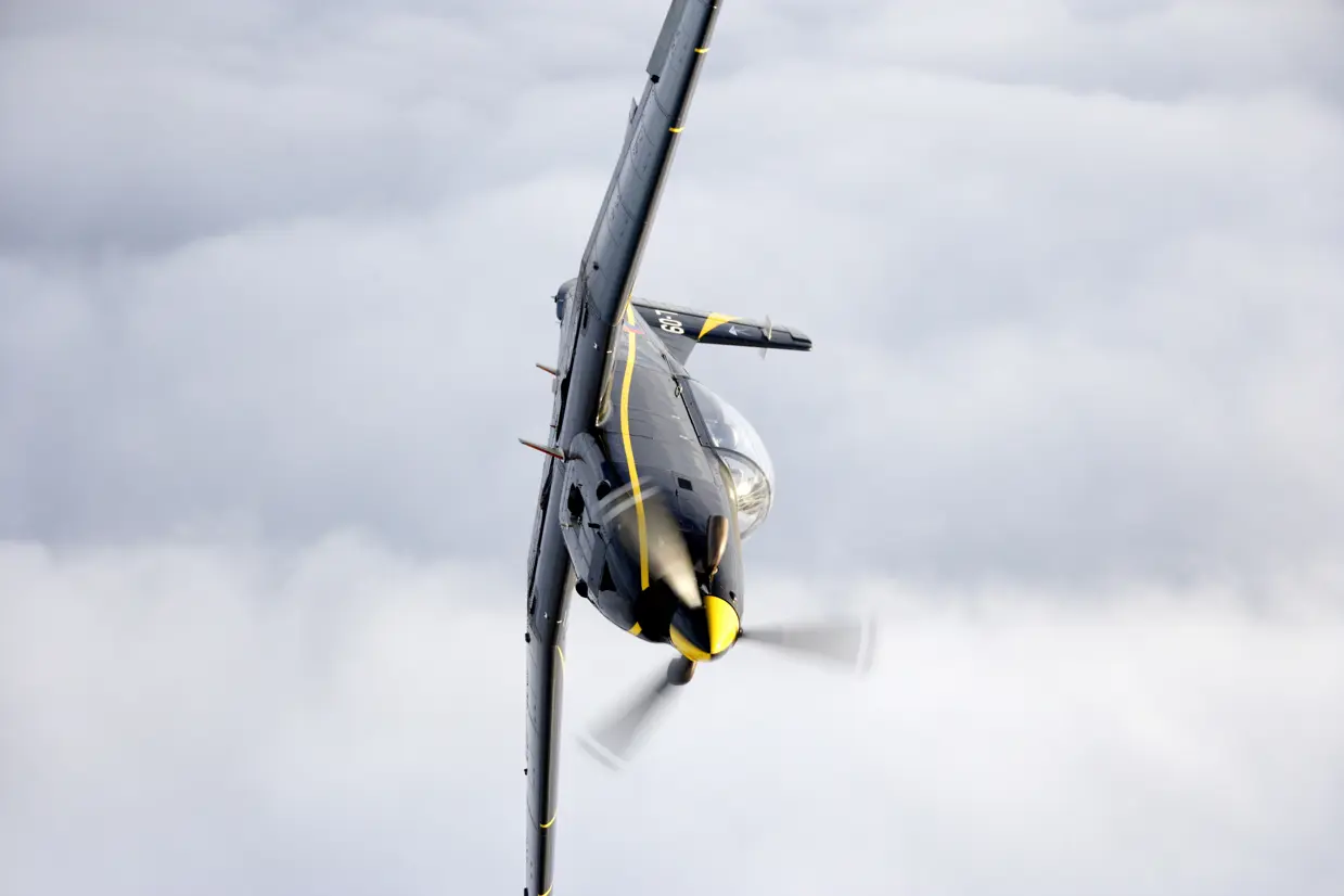 Zijaanzicht PC-7 in de lucht.