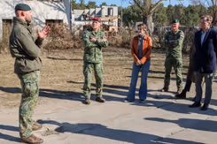 De minister en enkele militairen luisteren naar een andere militair.