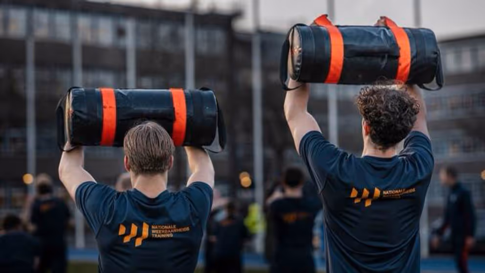 2 mannen op de rug gezien houden dikke zwarte rol boven hun hoofd.