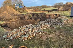 Grote hoeveelheid  opgestapelde granaten in grasland.