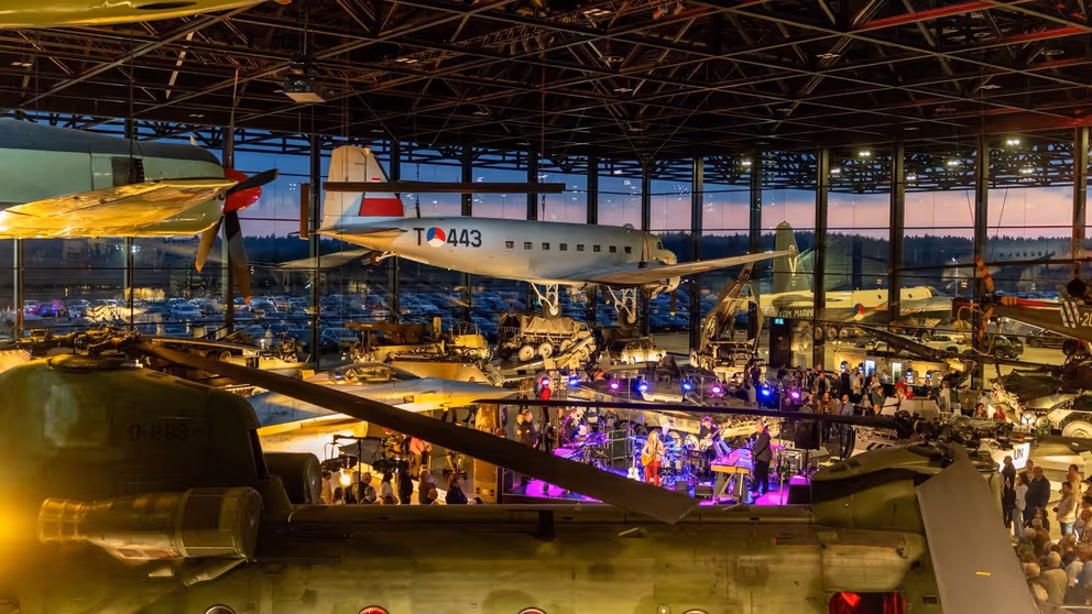 Bovenaanzicht van museumvloer met vliegtuigen die aan het plafond zijn bevestigd en mensen eronder.