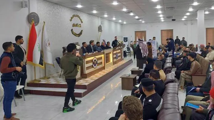 De minister spreekt een zaal toe in Irak.