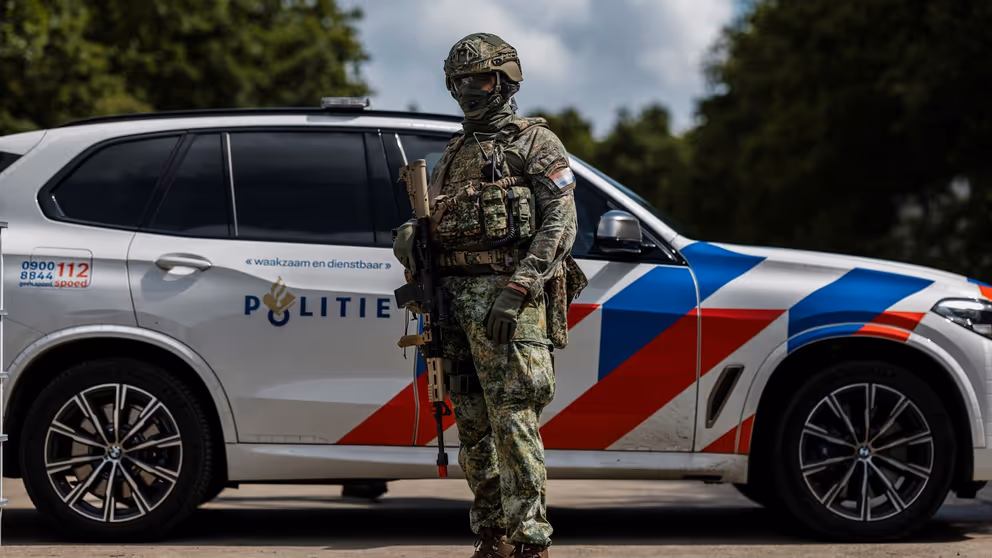 Militair poseert voor een politieauto.