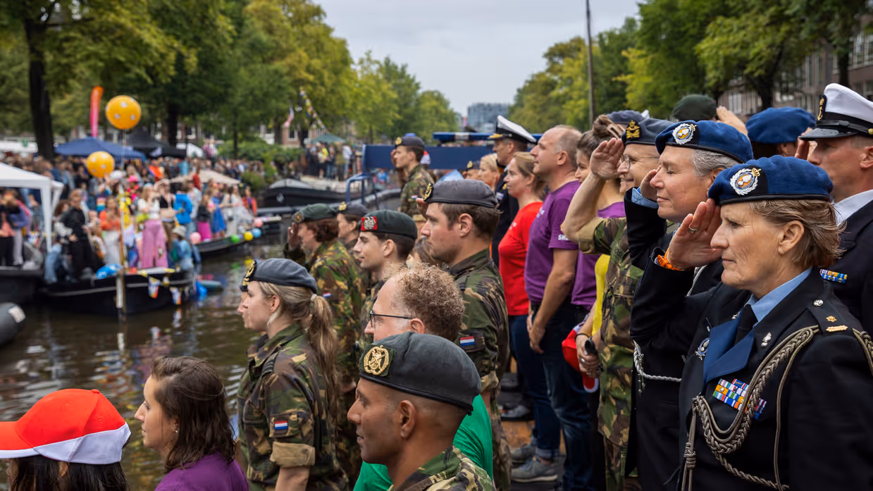 Militairen salueren vanaf een boot in de gracht.
