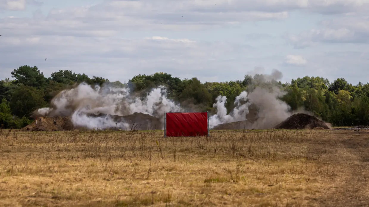 Rook stijgt op na een ontploffing. Op de voorgrond is een rood hek te zien.