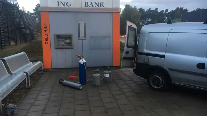 Geldpunt van een ING-bank. Voor het geldpunt staan gasflessen en een auto.