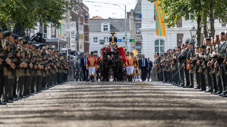 De Koninklijke stoet omringt door militairen. 