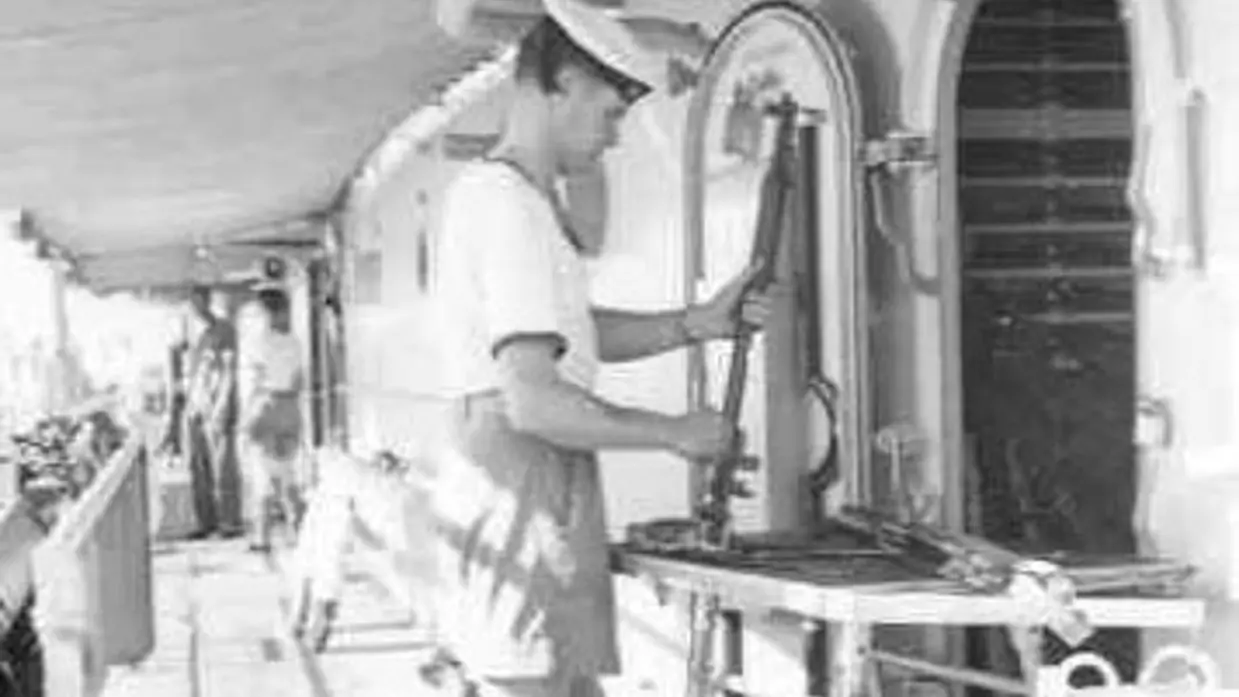 Marineman maakt geweer schoon aan boord van schip (1955).