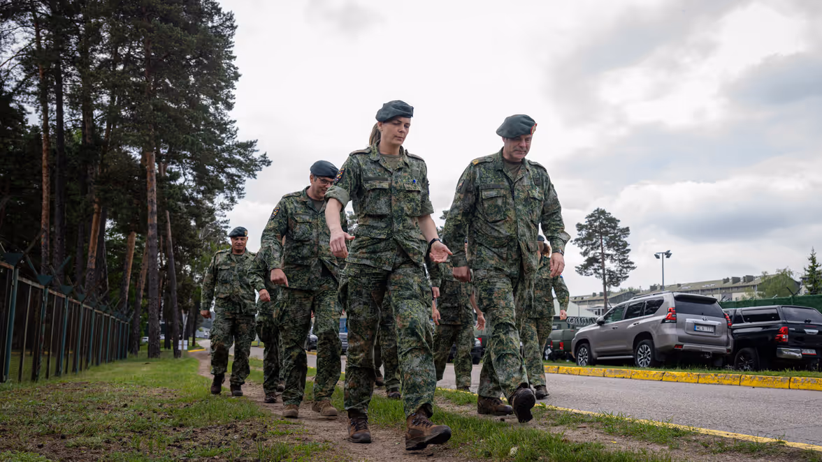 Militairen lopen door de berm van een weg. 
