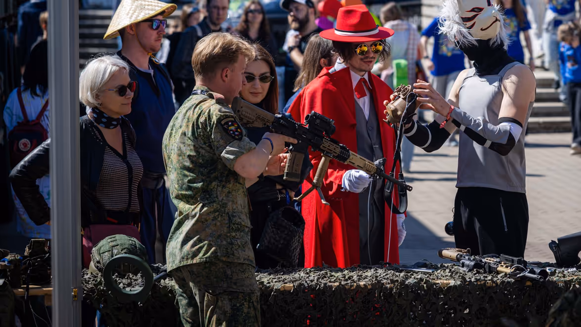 Een militair toont zijn geweer aan een burger. Een militair speelt een videogame.