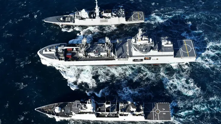 Drie schepen varen naast elkaar; onder in beeld Zr.Ms. Evertsen.