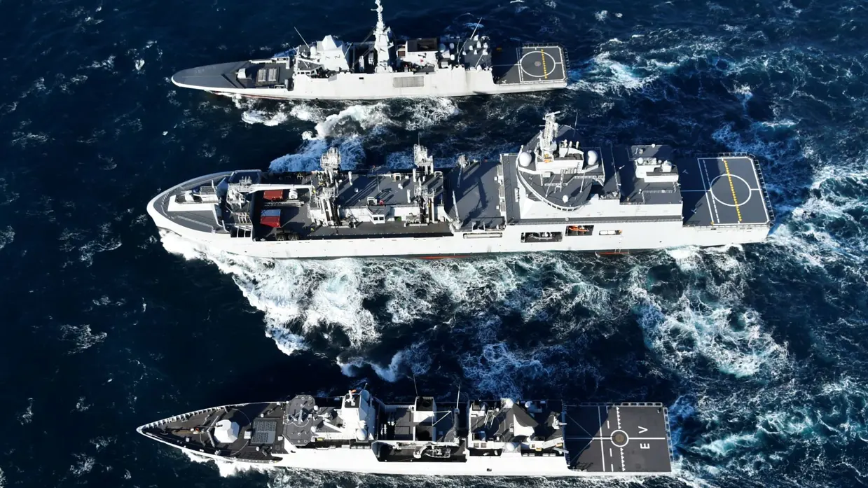 Drie schepen varen naast elkaar; onder in beeld Zr.Ms. Evertsen.