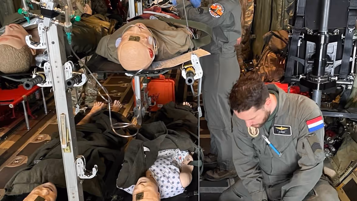 Luchtmachtmilitairen staan in het vrachtruim van een C-130 en verzorgen patiënten op brancards.
