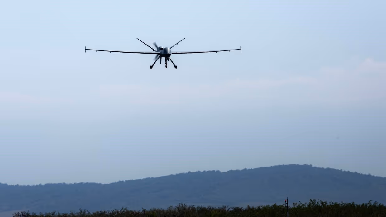 Een MQ-9 Reaper in de lucht in Roemenië met op de achtergrond een berg